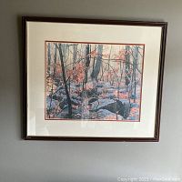 Full view of framed watercolor print depicting an autumn woodland scene with rocks and trees, framed by a wood frame.