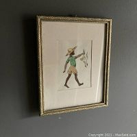 Framed watercolour painting hung on dark wall, showing full view of frame and artwork.