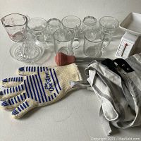 Full lot laid out on white surface showing glassware, glove, apron, vintage baster, and scale.
