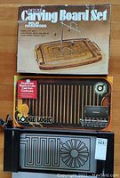Photo of Deluxe Carving Board Set box showing solid hardwood carving board with meat holder and fork, Lodge Logic sealed cast iron griddle with pro grid surface, and Salton warming tray with geometric heating element design.