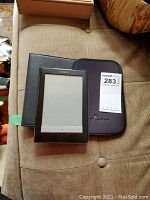 Sony PRS-600 digital reader and protective case on a couch surface.