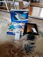 Full view of the three main items: Samsung DVD player box, Dazzle Digital Creator 90 box unopened, Insignia digital frame with power cable and remote.