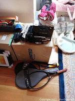 Overall view of lot showing tennis rackets, mitts, helmet, and packing boxes.