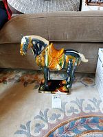 Full view of ceramic horse statue showing multi-color glaze and saddle detail.