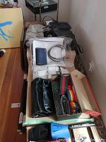 Photo showing multiple handbags, some vinyl and cloth, luggage straps rolled and unrolled in various colors, and packaged pantyhose.