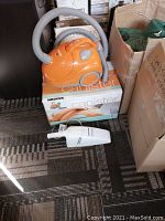 Image showing the Hoover orange canister vacuum model S1361 on its box and the white Black & Decker Dustbuster cordless vacuum in front.