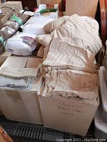 Overall view of the bedding items including folded sheets, duvets, and mattress covers packed in a box and placed on a table