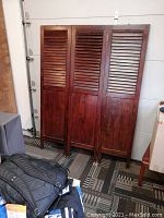 Full view of the wooden three-panel room divider showing louvered upper panels and solid wood lower panels.