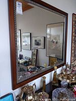 Front view of the large rectangular framed mirror showing wood and metal trim details, reflecting interior room with art and decor.