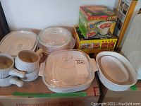 Photo of all ceramic dishes including casserole dishes with lids, soup bowls, and serving bowls alongside boxed microwave rice cooker and steamer