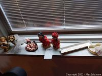 Various figurines and decorative items placed on a windowsill including ceramic figurines, blown glass piano and bench, trinket dishes
