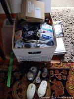 Box containing multiple miscellaneous cables, computer mice, and electronic accessories.