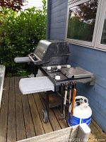 Full view of Weber Genesis Gold grill on deck with side shelves, hot plates, control knobs, and propane tank.