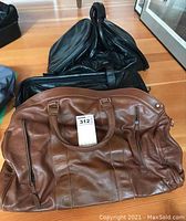 Overall view of three leather bags stacked showing condition and size