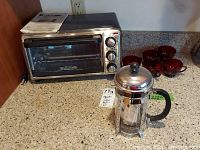 Black & Decker toaster oven, Bodum coffee press, and six red coffee glasses on kitchen counter