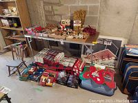 Photo showing two shelves loaded with multiple boxes of Christmas lights of various types, vintage glass ornaments, and several fabric Christmas stockings with festive appliqué.