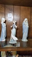 View of all three figurines on glass shelf showing Lladro and RR Roman Madonna and Child