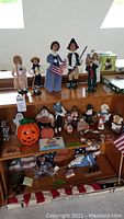 Overview of mixed holiday decorations displayed on wooden shelves including figurines, pumpkin, and flags.