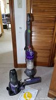 Dyson upright vacuum and Shark cordless vacuum displayed on floor, showing overall size and shape.