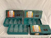 Five glasses in original green Salzburg Crystal boxes, showing the cut crystal pattern and packaging design