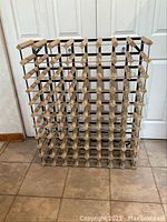 Front view of the wood and metal wine rack showing the grid structure and individual slots for bottles.