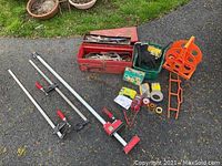 Wide shot of all items laid out including toolbox, bar clamps, cord reel, tapes, gloves, and tape measure