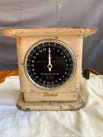 Front view of rusty cream-colored vintage Record mechanical weight scale showing large black dial and round chrome bezel.