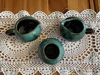 Three-piece set on lace doily: two pitchers and one bowl showing top view