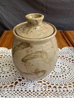 Front view of the large pottery crock canister showing body shape, lid, and surface color pattern