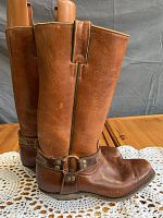 Side view of the brown leather cowboy boots showing harness straps and metal details.