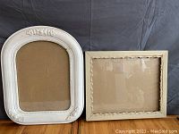 Both rustic antique picture frames side by side on a dark cloth background showing overall condition and size difference.