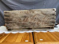 Side view of the antique wooden Coca Cola crate showing faded logo and aged wood.