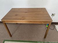 Front view of the rectangular wooden Ikea table with visible natural finish and four legs.