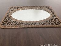 Top-down view of the rectangular mirror showing detailed scrollwork and oval reflective surface in the frame.