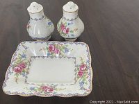 Photo showing salt and pepper shakers with butter dish on wooden surface