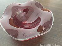 Top view showing the wavy rim and the glossy finish of the deep red glass bowl.