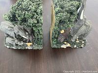 Pair of elephant book ends shown side by side depicting green trees and elephants