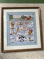 Full view of framed needlepoint artwork showing 'Old McDonald had a farm' with animals and farm elements in colorful cross-stitch.