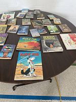 Books laid out on round table, showing full lot of 29 young men's novels