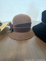 Brown cloche style vintage dress hat with wide velvet band and flower detail on side.