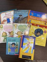 Photo of eight French and bilingual children's books laid out on a table. Various colorful illustrated covers with titles visible.