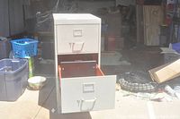Full view of the beige metal filing cabinet with the top and middle drawer closed, bottom drawer opened showing the bright orange interior.