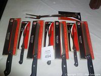 Photo of the full set showing four serrated bread knives and four utility forks in original packaging, laid out on a white surface.