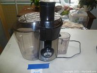 Full view of Hamilton Beach juicer showing large clear pulp container, juice container and main body with power cord and dial.