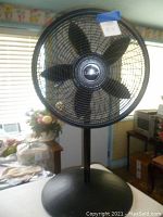Front view of black Lasko pedestal fan showing blades and brand name on center hub.