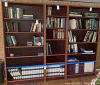 Front view of bookshelf displaying three large sections with multiple shelves, currently holding books.