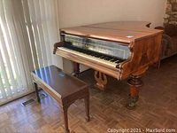 Three-quarter front view of grand piano with bench alongside