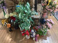 Wide view of multiple faux flower arrangements near stone fireplace and wood floor, showing variety and colors of items.