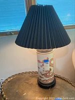 Front view of Asian-style ceramic lamp with red dragon design on cream base and black pleated shade