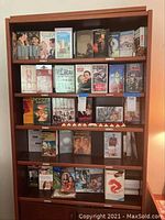 Full view of bookshelf loaded with a variety of VHS movie tapes including titles and cover art visible